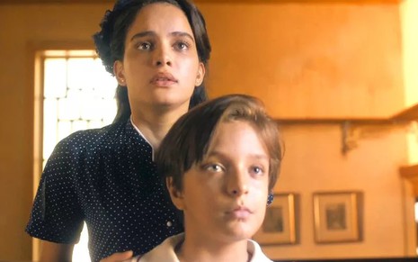 Inês (Carol Macedo) e Leon (Kaio Antunes) com expressão assustada em cena de Éramos Seis