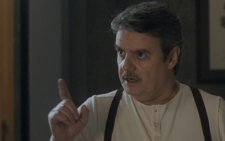 O ator Cássio Gabus Mendes, de suspensório e pijamas, aponta o dedo para a esquerda, com expressão de confronto, caracterizado como o Afonso em cena de Éramos Seis