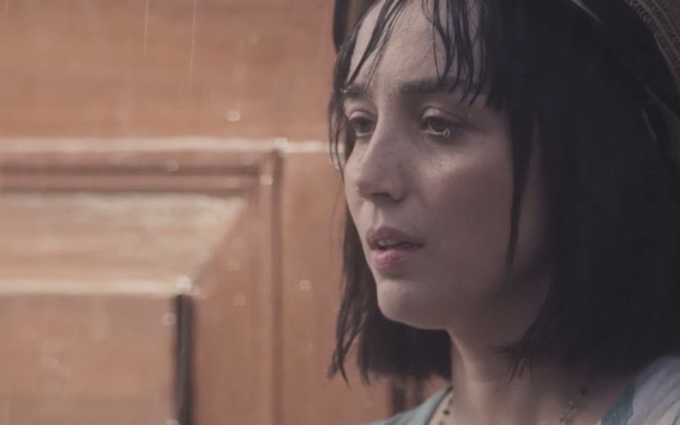A atriz Simone Spoladore olha para o nada em cena de chuva da novela das seis da Globo, Éramos Seis, em que interpreta Clotilde