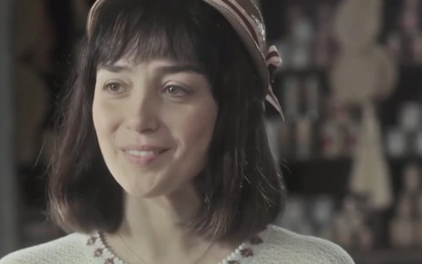 A atriz Simone Spoladore sorri caracterizada como a Clotilde em cena de Éramos Seis