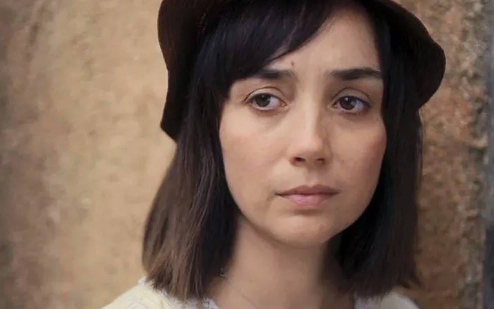 A atriz Simone Spoladore, em close, com um pequeno chapéu, caracterizada como a Clotilde em cena de Éramos Seis