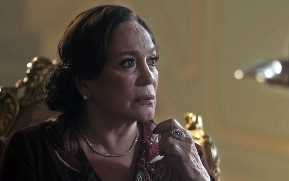 A atriz Susana Vieira caracterizada como a personagem Emília em cena de Éramos Seis, sentada em uma poltrona