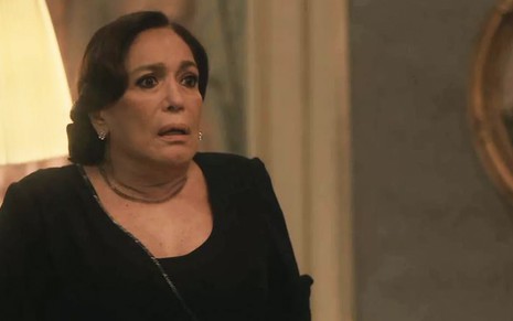 A atriz Susana Vieira, com um vestido preto e expressão de espanto, caracterizada como a Emília em cena de Éramos Seis