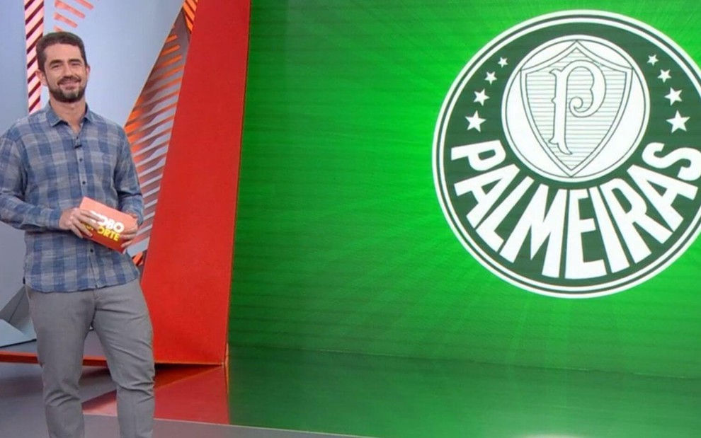 Felipe Andreoli no estúdio do Globo Esporte SP, ao lado de um telão com o escudo do Palmeiras