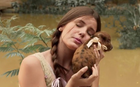 A atriz Camila Queiroz com o rosto colocado em uma porquinha em cena de Êta Mundo Bom!