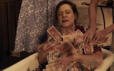 A atriz Elizabeth Savalla caracterizada como Cunegundes dentro de uma banheira e coberta por cédulas de dinheiro em cena de Êta Mundo Bom!