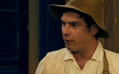 Com um chapéu caipira na cabeça, o ator Sergio Guizé fica chocado em cena da novela Êta Mundo Bom!