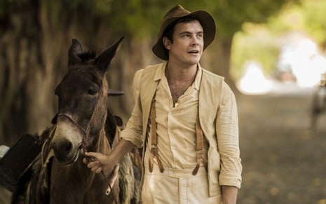 O ator Sergio Guizé, caracterizado como o caipira Candinho, puxa o burro Juca, o Policarpo, na novela Eta Mundo Bom!