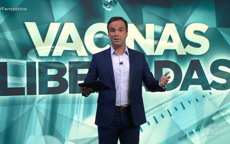 Tadeu Schmidt no comando do Fantástico no domingo (17), com o telão com uma arte de vacinas liberadas ao fundo
