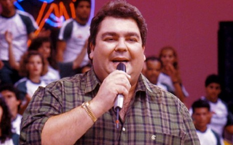 Fausto Silva de camisa xadrez e microfone na mão em foto de 1989