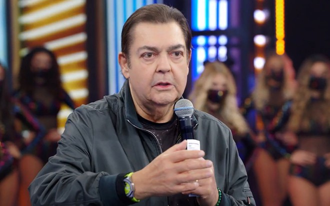 O apresentador Fausto Silva no cenário do Domingão do Faustão com bailarinas ao fundo