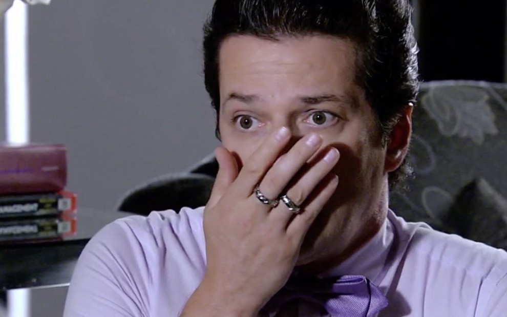 O ator Marcelo Serrado caracterizado como Crô, personagem de Fina Estampa: Crô usa uma camisa lilás e faz cara de surpreso