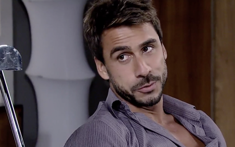 O ator Julio Rocha caracterizado como Enzo em Fina Estampa: personagem faz olhar de sedutor e usa camisa cinza escura entreaberta