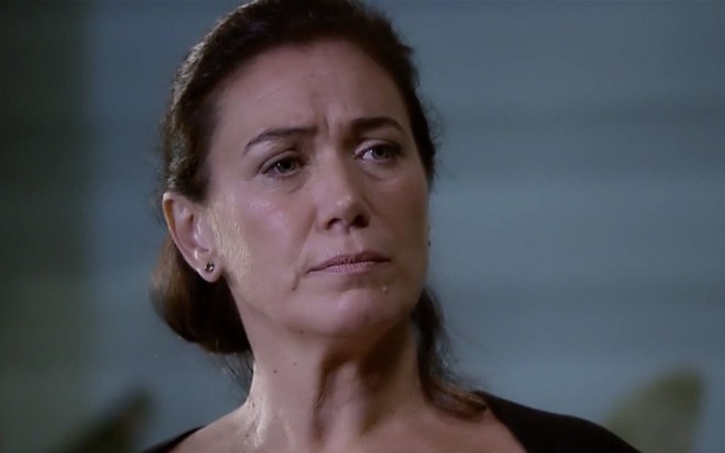 A atriz Lilia Cabral caracterizada como Griselda em Fina Estampa; personagem está de camiseta preta e tem olhar de desconfiança