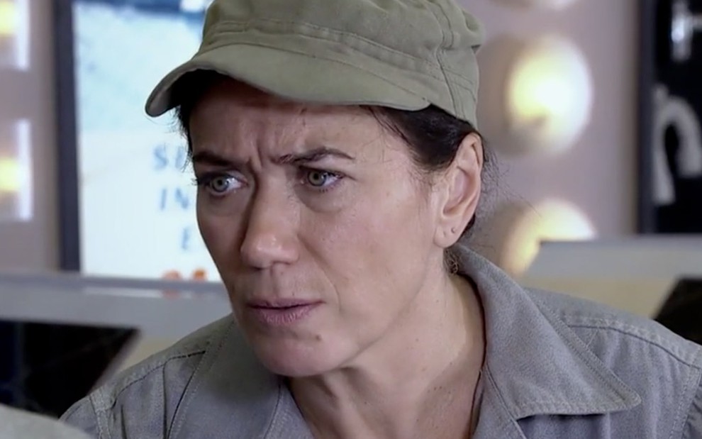 A atriz Lilia Cabral caracterizada como Griselda da Fina Estampa, personagem está de boné verde militar e macacão cinza