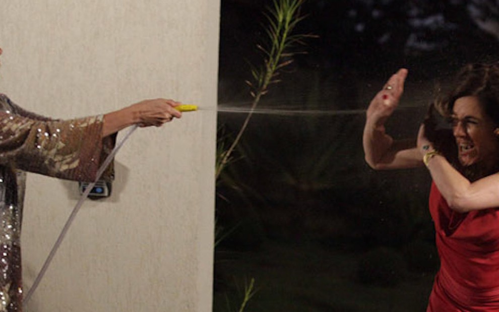 A atriz Lilia Cabral esguicha água com uma mangueira em Christiane Torloni em gravação da novela Fina Estampa, da Globo