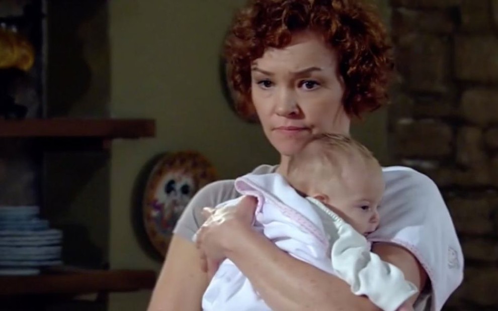 A atriz Julia Lemmertz caracterizada como Esther, da novela Fina Estampa, segura um bebê recém-nascido, interpretado por Larissa Cunha Brito
