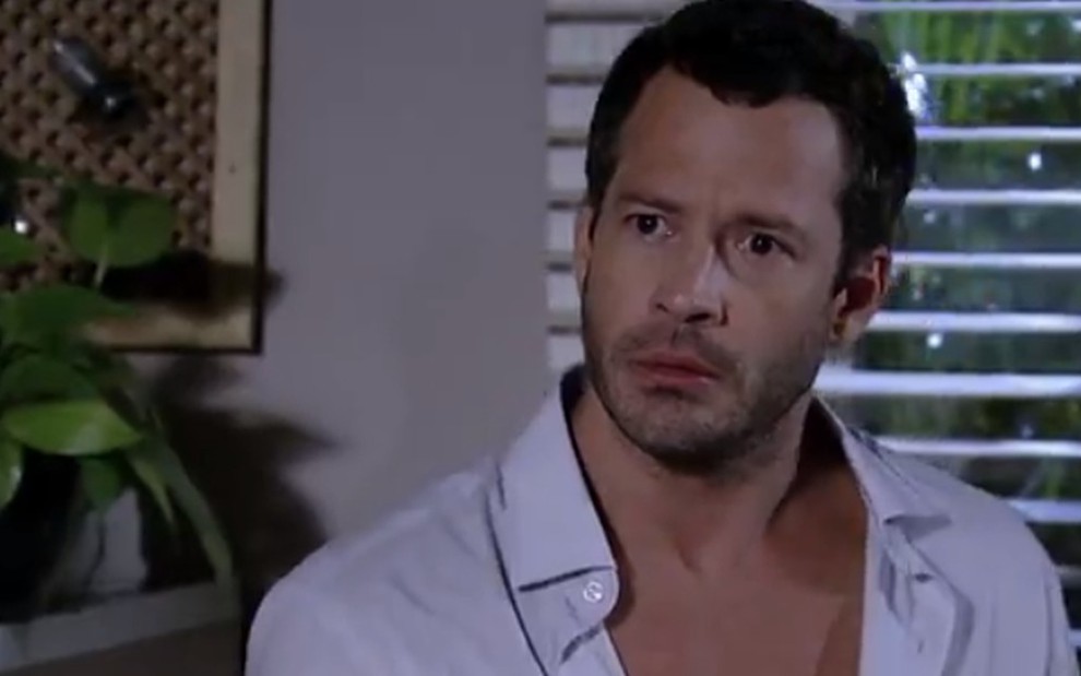 O ator Malvino Salvador, usando uma camisa branca de botões, aberta mostrando o peito, com expressão preocupada, em cena como Quinzé na novela Fina Estampa