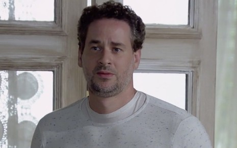 Dan Stulbach caracterizado como Paulo em Fina Estampa: personagem faz cara de pena e usa uma blusa de manga comprida branca