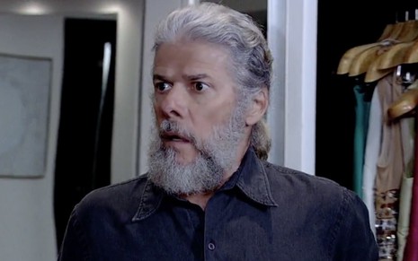 José Mayer caracterizado como o personagem Pereirinha, de Fina Estampa: ator usa camisa preta e está com o cabelo grande e barba espessa