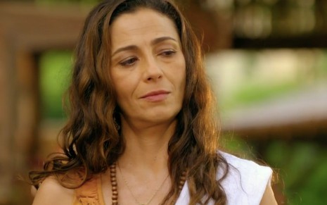 A atriz Cyria Coentro caracterizada como a Bibiana com um pano de prato no ombro direito em cena de Flor do Caribe