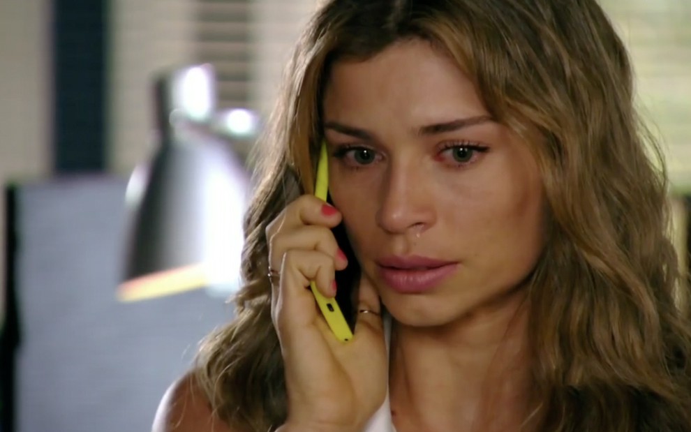 A atriz Grazi Massafera com lágrimas nos olhos fala ao celular como Ester em cena de Flor do Caribe