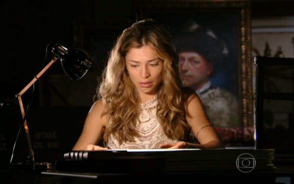 A atriz Grazi Massafera, observando um livro, em cena como Ester em Flor do Caribe