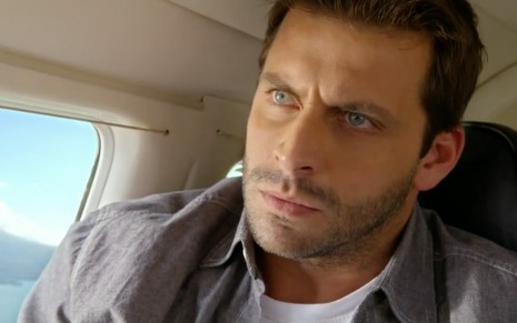 O ator Henri Castelli caracterizado como Cassiano dentro de um avião particular com expressão de preocupação em cena de Flor do Caribe