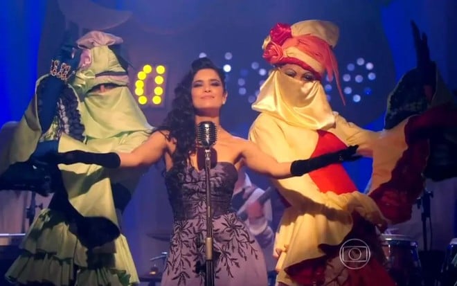 A atriz Moro Anghileri em cena como a cantora Cristal, cantando em um palco, na novela Flor do Caribe