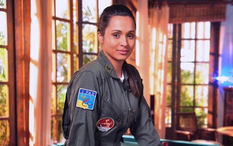 Thaissa Carvalho caracterizada como Isabel em Flor do Caribe: atriz usa uniforme da aeronáutica e sorri para câmera
