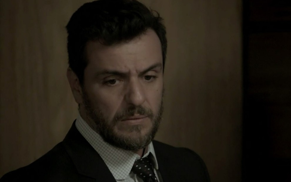 Rodrigo Lombardi caracterizado como Caio em A Força do Querer; ator olha para o chão e tem semblante triste