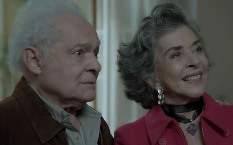Othon Bastos e Betty Faria em cena de A Força do Querer: ator olha de maneira séria para fora do quadro e atriz sorri para a mesma direção