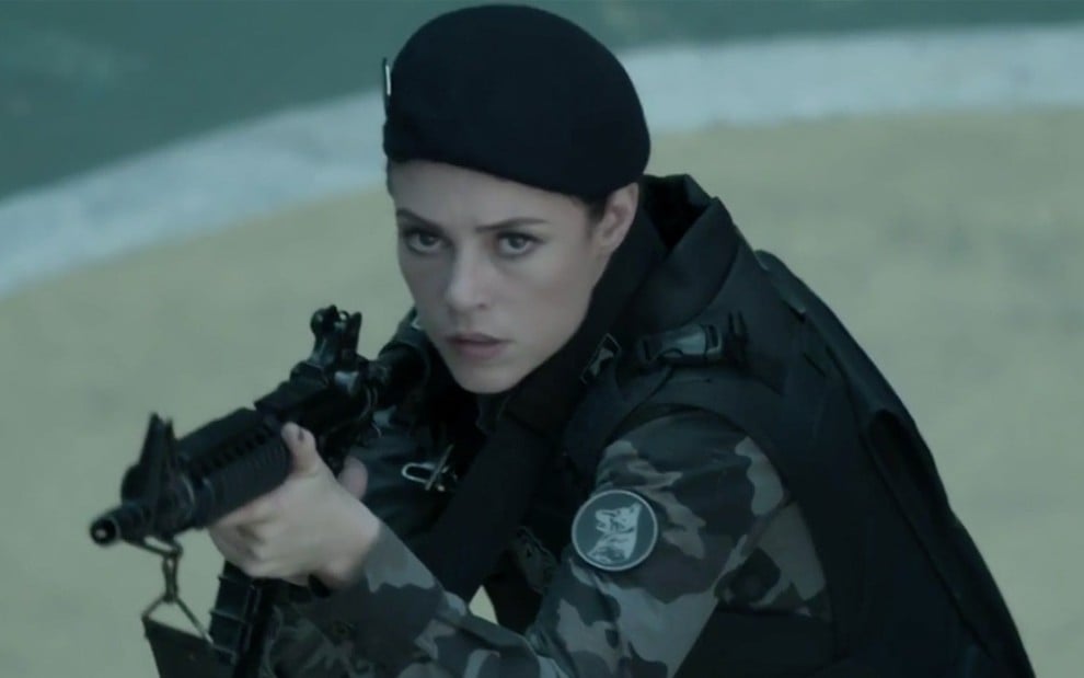 Paolla Oliveira caracterizada como Jeiza em A Força do Querer; personagem segura uma arma e olha com atenção para o ambiente ao seu redor