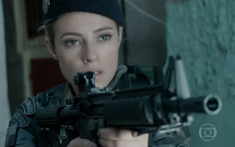 Paolla Oliveira em cena de A Força do Querer: caracterizada como Jeiza, atriz usa uniforme policial e segura um fuzil