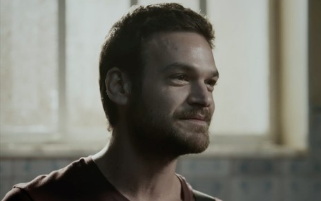 Emilio Dantas caracterizado como Rubinho em A Força do Querer: personagem sorri de lado para alguém fora do quadro