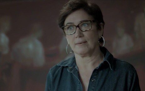 Lilia Cabral caracterizada Silvana em A Força do Querer: personagem usa óculos, brinco de argola e tem olhar incrédulo para alguém fora do quadro
