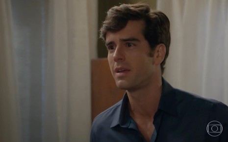 O ator Marcos Pitombo faz uma expressão de revolta e desespero em cena de Haja Coração na qual usa uma camisa marinho