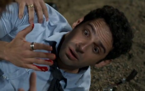 O personagem Beto (João Baldasserini) olha para mão ensanguentada com sangue cenográfico em cena da novela Haja Coração, da Globo