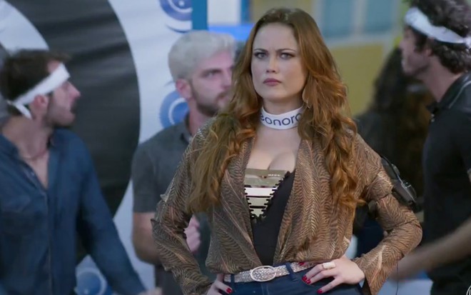Ellen Rocche em cena de Haja Coração: caracterizada como Leonora, personagem faz cara de reprovação dentro da casa de vidro do BBB