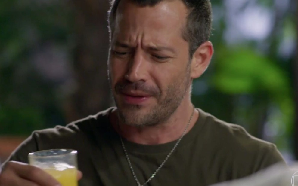 O personagem Apolo (Malvino Salvador) olha com careta para um copo de suco em cena da novela Haja Coração, da Globo