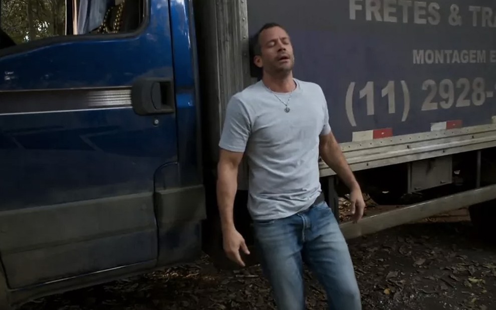 O ator Malvino Salvador faz expressão de dor como Apolo e está encostado em um caminhão em cena de Haja Coração