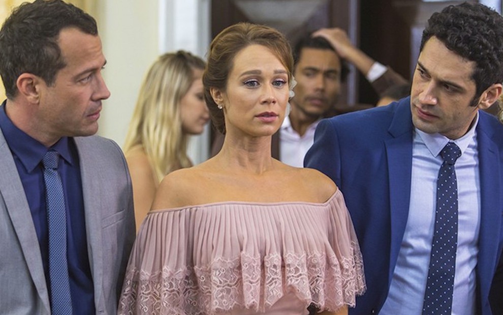 De terno e gravata, Malvino Salvador olha para Mariana Ximenes (ao centro), que também é encarada por João Baldasserrini em cena de Haja Coração