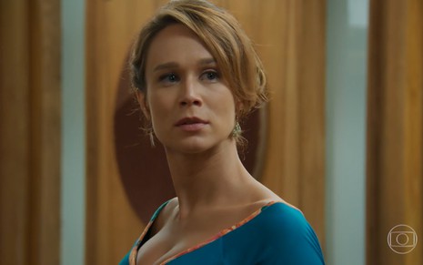 Mariana Ximenes com uma blusa decotada azul e expressão séria como Tancinha de Haja Coração