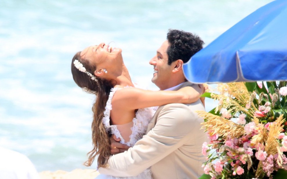 Vestida de noiva, Mariana Ximenes abraça João Baldasserini, que está de terno, durante gravação de cena de Haja Coração