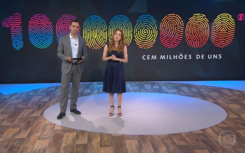 Tadeu Schmidt e Poliana Abritta no Fantástico, com o logo da campanha 100 Milhões de Uns ao fundo