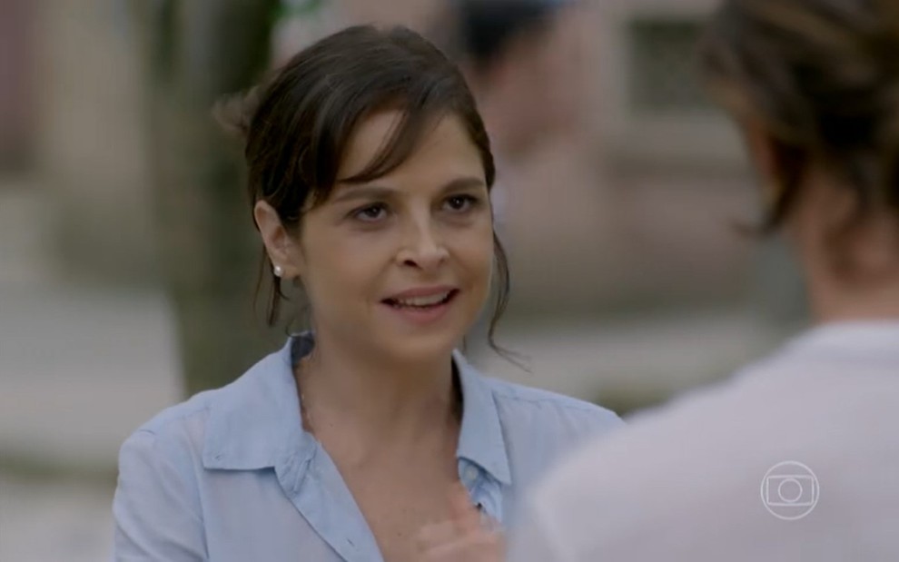 Drica Moraes grava cena de Império com camisa azul e cabelo preso, conversando com Romulo Arantes Neto, de costas na sequência