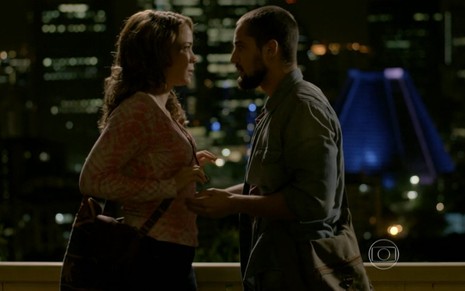 Leandra Leal e Rafael Cardoso gravam cena em viaduto com luzes da cidade iluminando a noite; ele pega no braço dela e ela se afasta em Império