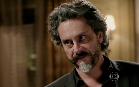 O ator Alexandre Neto, com barba e bigode, usa camisa preta em gravação de cena da novela Império, da Globo