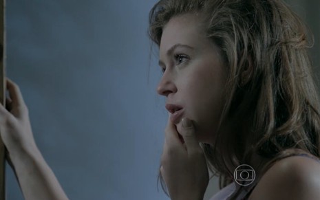 Marina Ruy Barbosa grava com a mão perto dos lábios olhando para Daniel Rocha, que não aparece na foto, como Maria Isis de Império