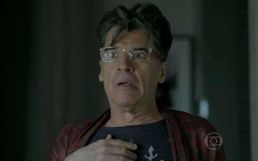 Paulo Betti grava com óculos de grau, mão no peito e expressão de espanto como Téo de Império, novela das nove da Globo